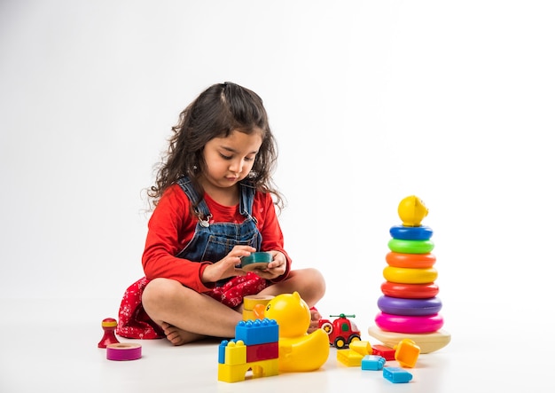 Linda garotinha indiana asiática brincando com brinquedos de blocos coloridos sobre fundo branco