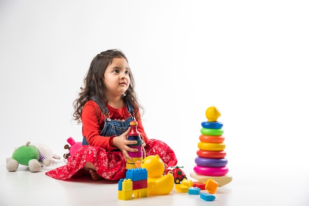 Linda garotinha indiana asiática brincando com brinquedos de blocos coloridos sobre fundo branco