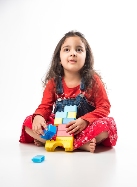 Linda garotinha indiana asiática brincando com brinquedos de blocos coloridos sobre fundo branco