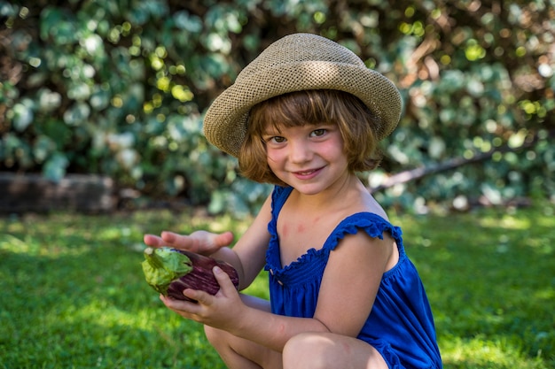 Linda garotinha loira colhendo legumes orgânicos na fazenda