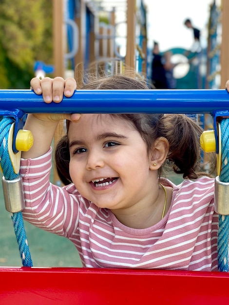 linda garotinha no playground sorri e olha para o quadro, foto no telefone