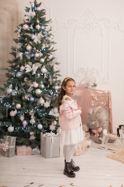 Linda garotinha posando perto da árvore de Natal.