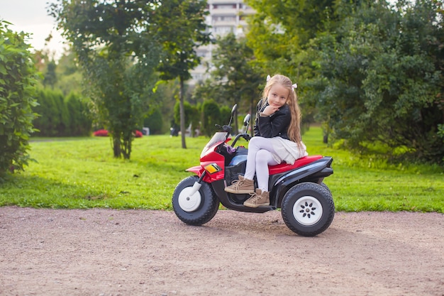 Linda garotinha se divertindo em sua bicicleta de brinquedo no parque verde