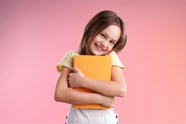Linda garotinha sorridente segurando um livro colorido