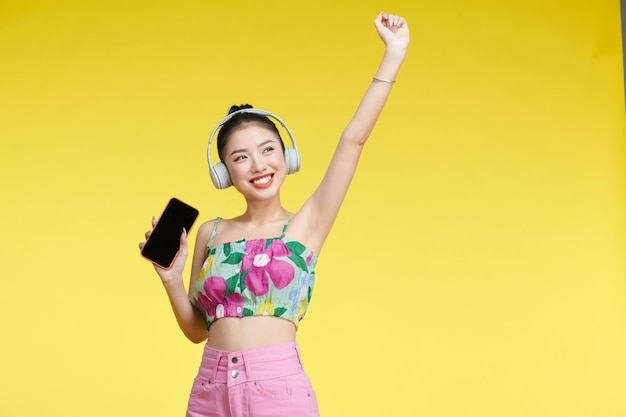 Linda hermosa mujer escuchando música con auriculares inalámbricos aislado sobre fondo amarillo