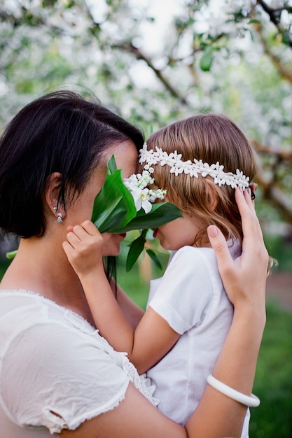 Linda hija y madre abrazándose en flor jardín de primavera