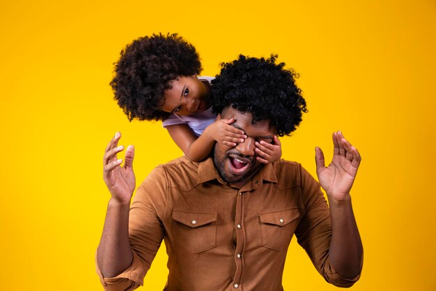 Linda hija pequeña africana cerrando los ojos de su padre niña haciendo sorpresa preparando un regalo en el día del padre divirtiéndose con papá