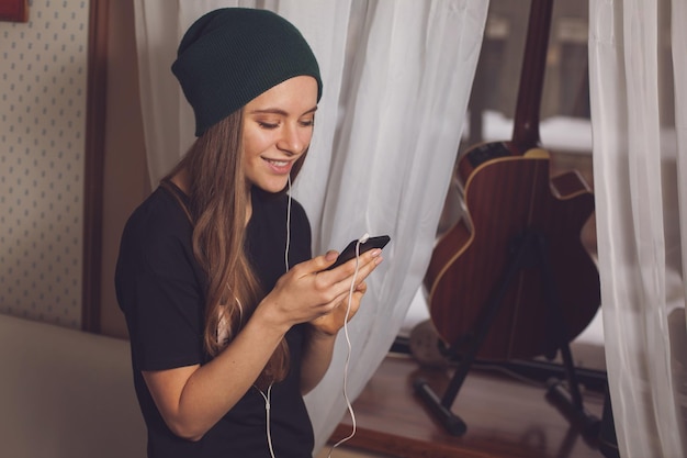 Linda hipster mujer escuchando música cerca de la guitarra