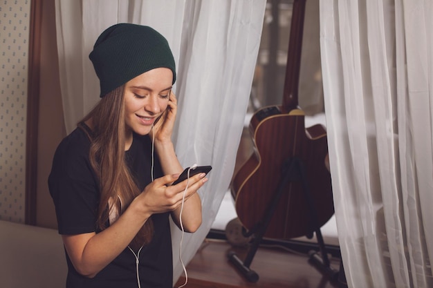 Linda hipster mujer escuchando música cerca de la guitarra