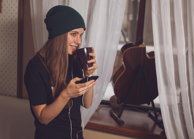 Linda hipster mujer escuchando música cerca de la guitarra