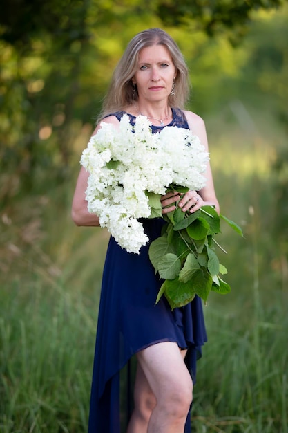 Linda idosa posando no jardim com um buquê de flores