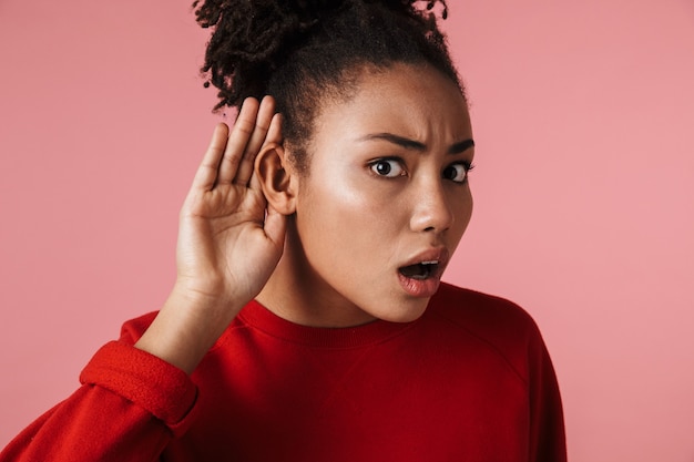 linda incrível jovem chocada mulher africana posando isolada sobre a parede rosa tentar ouvir você.