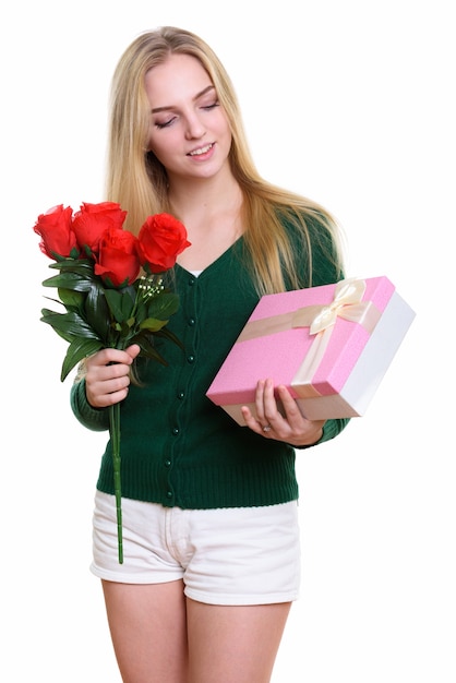 Foto linda jovem adolescente segurando rosas vermelhas e uma caixa de presente