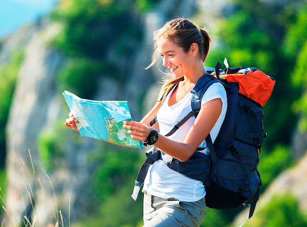 Linda jovem alpinista com mochila e mapa