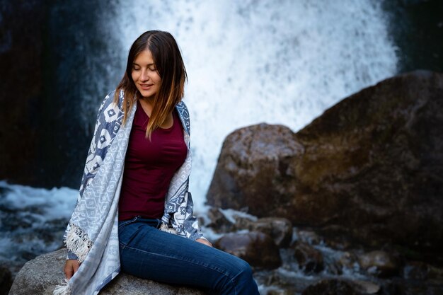 Linda jovem alpinista sentada perto da cachoeira