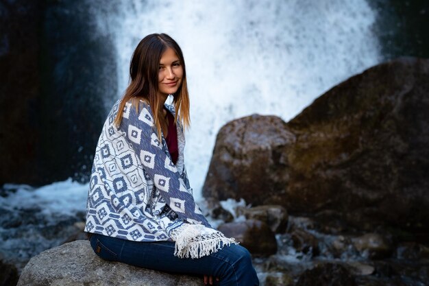 Linda jovem alpinista sentada perto da cachoeira