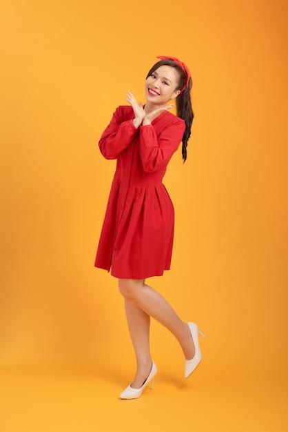 Linda jovem asiática com vestido vermelho sobre fundo laranja Comprimento total