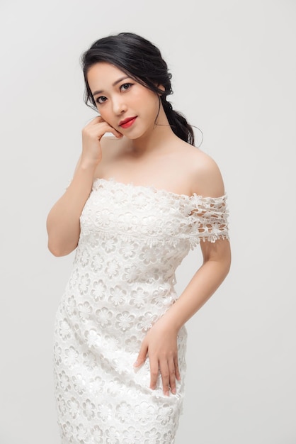 Linda jovem asiática de vestido branco posando no fundo branco