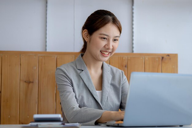 Linda jovem asiática olhando para informações em uma imagem de conceito de laptop de mulher de negócios asiática trabalhando mulher de negócios de inicialização executiva moderna inteligente mulher líder de negócios mulher