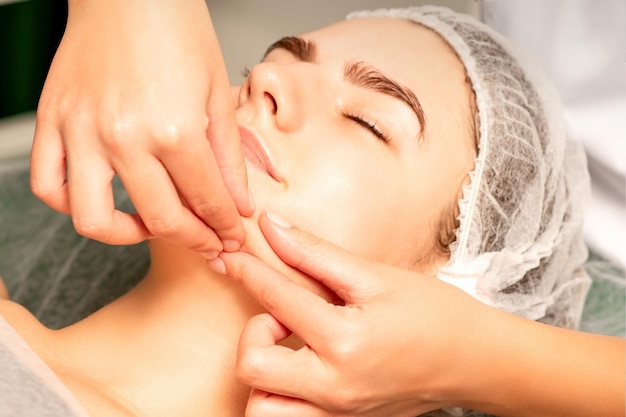 Foto linda jovem caucasiana com os olhos fechados, recebendo uma massagem facial em um salão de beleza