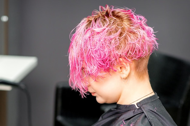 Linda jovem caucasiana de cabelo rosa no salão de cabeleireiro moderno