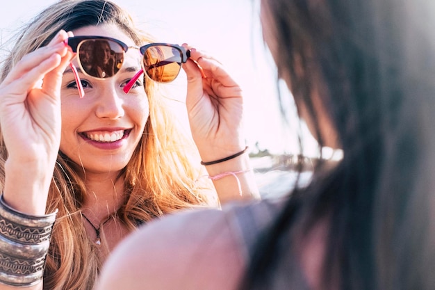 Linda jovem caucasiana usa os óculos de sol para espelhar as amigas de verão e conceito de férias e férias para pessoas alegres atraentes em atividades de lazer ao ar livre