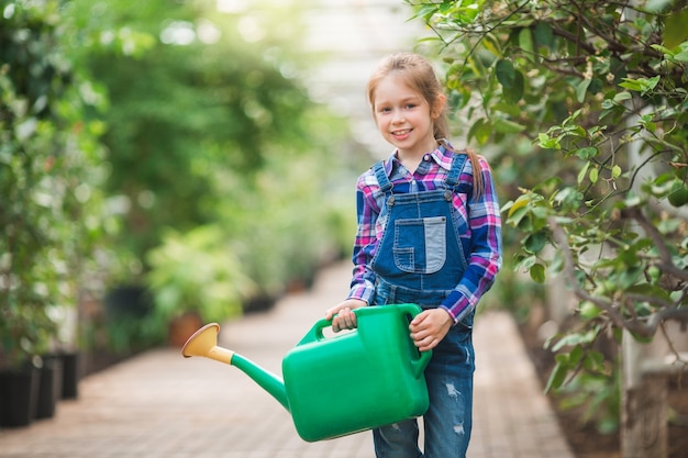 Foto linda jovem com um regador nas mãos no jardim da estufa