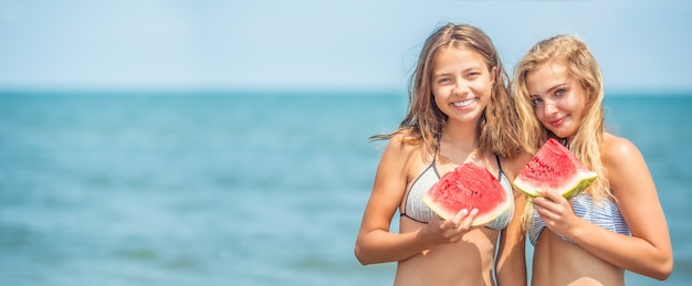 Linda jovem comendo melancia fresca na praia tropical.