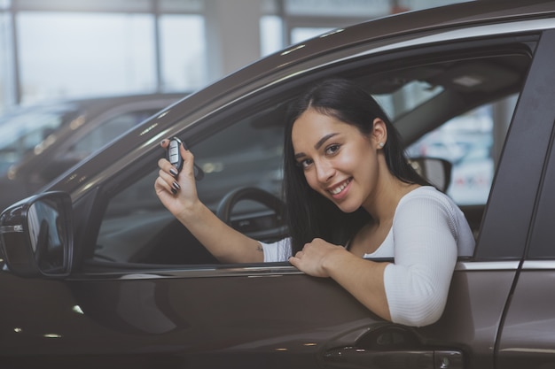 Linda jovem comprando carro novo na concessionária