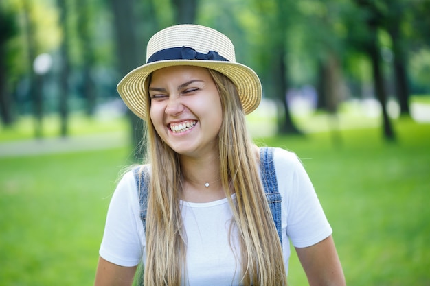 Linda jovem de macacão jeans e um chapéu leve caminhando no parque