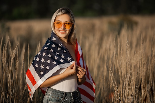 linda jovem de óculos escuros com a bandeira americana