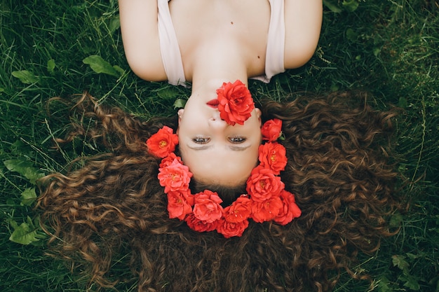 Foto linda jovem deitada na grama com guirlanda de flores