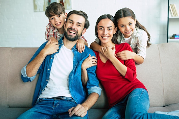 Linda jovem família feliz relaxando juntos em casa sorrindo e abraçando