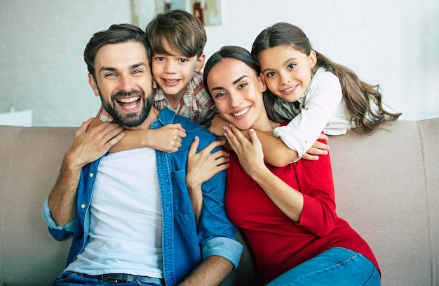 Foto linda jovem família feliz relaxando juntos em casa sorrindo e abraçando