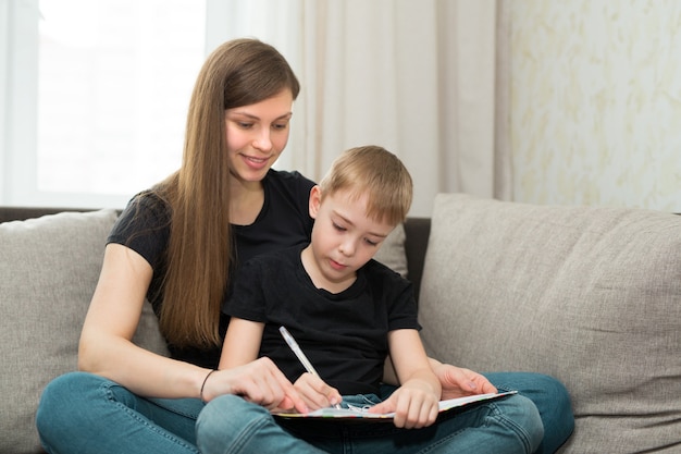 Linda jovem família mãe e filho fazendo lição de casa