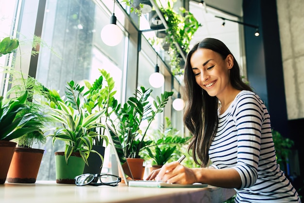 Linda jovem feliz com laptop no café da cidade