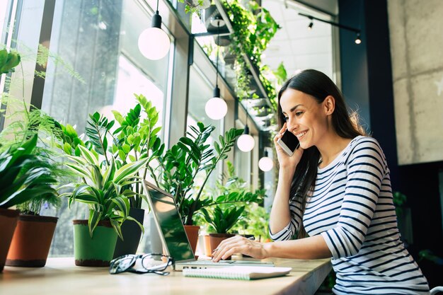 Linda jovem feliz com laptop no café da cidade