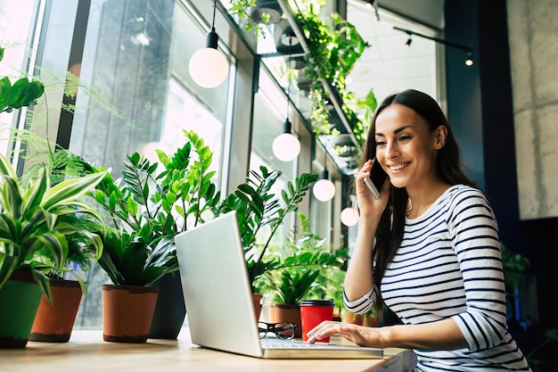 Linda jovem feliz com laptop no café da cidade