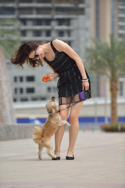 linda jovem feliz de vestido preto com cachorrinho fofo se divertir na rua