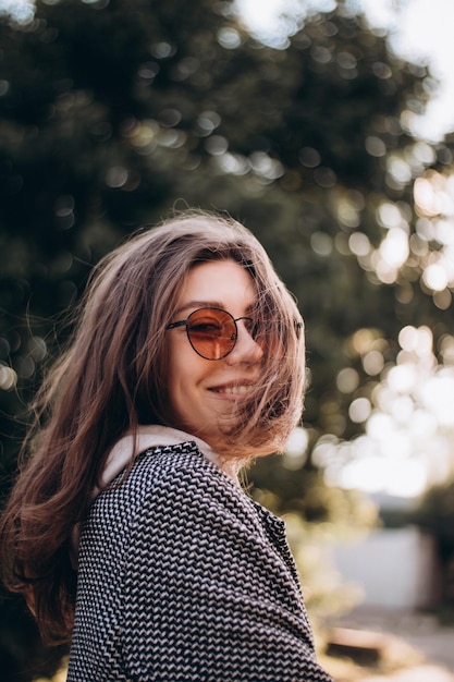 Linda jovem feliz em óculos de sol rindo na felicidade do parque