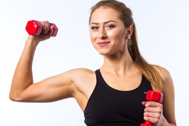 Linda jovem fitness caucasiana malhando com pesos de mão, braços estendidos, construindo força