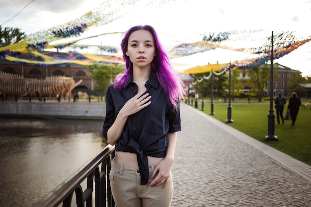 Linda jovem garota peluda violeta caminhando ao pôr do sol em um parque da cidade. São Petersburgo, Nova Holanda