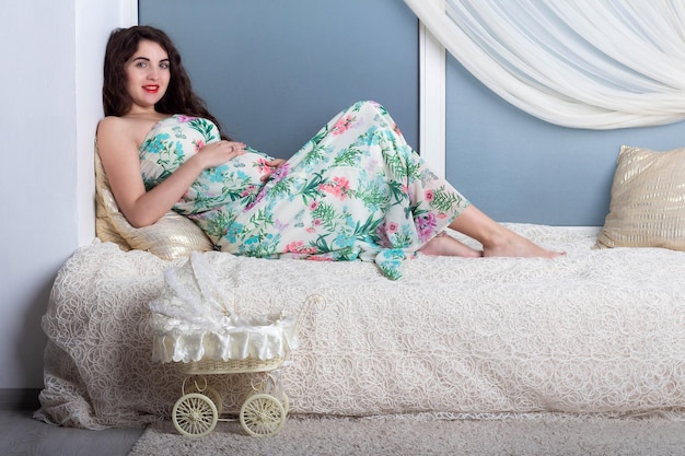 Linda jovem grávida com cabelo encaracolado em um vestido longo