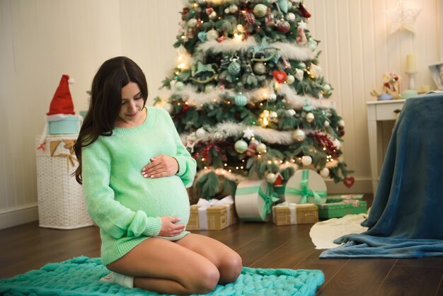 Linda jovem grávida decorando uma árvore de natal