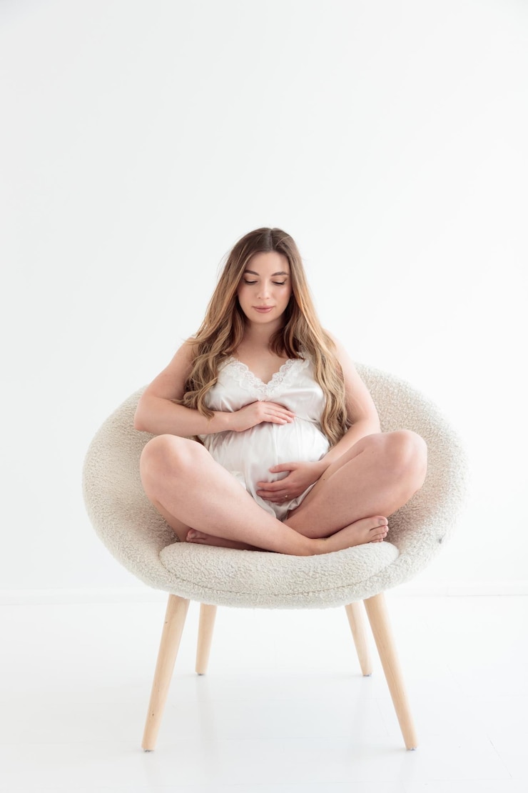 Linda jovem grávida relaxando em uma cadeira branca