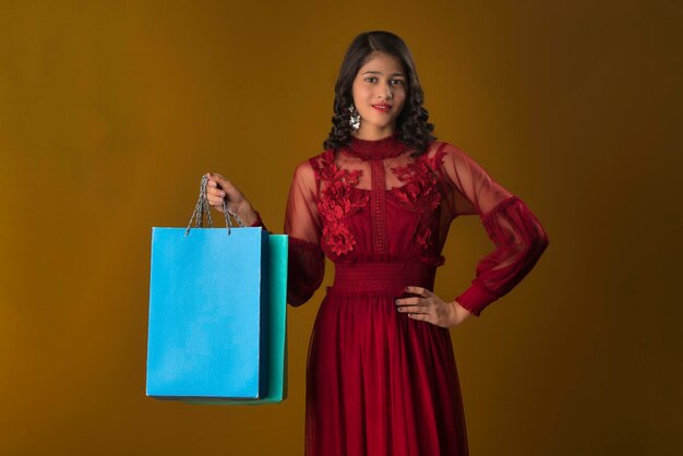 Linda jovem indiana segurando e posando com sacolas de compras em um fundo marrom