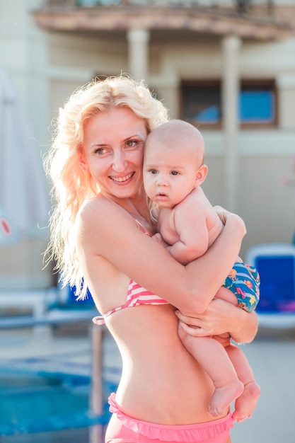 Linda jovem mãe com bebê na piscina