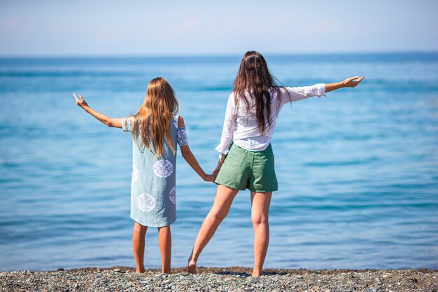 Linda jovem mãe e sua adorável filhinha se divertindo em uma praia tropical