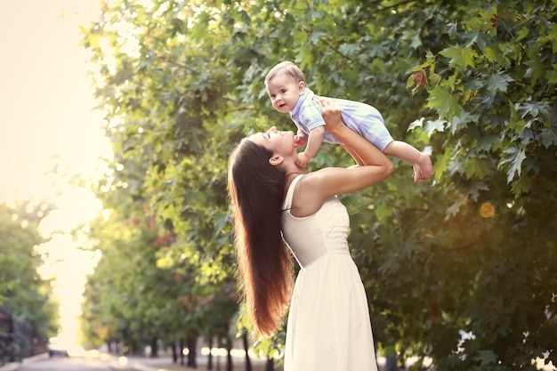 Linda jovem mãe segurando um lindo menino, ao ar livre