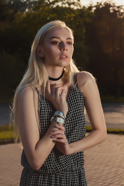 Linda jovem modelo usando calça, pulseira e macacão posando na cidade à noite